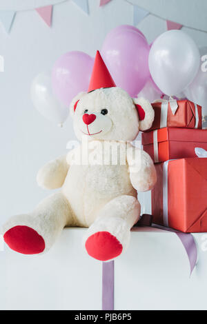 teddy bear in cone with gift boxes and air balloons Stock Photo