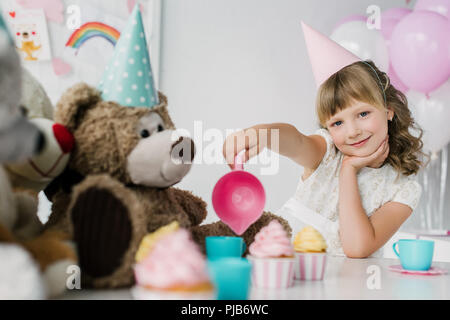 smiling birthday child having tea party with teddy bears in cones Stock Photo