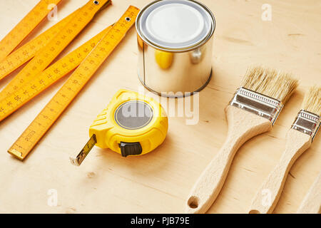 background with a ruler, tape measure, brushes and paint cans on a wooden board Stock Photo