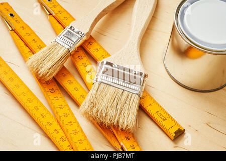 background with a ruler, paint brushes and paint cans on a wooden board Stock Photo
