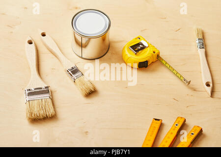 background with a ruler, tape measure, brushes and paint cans on a wooden board Stock Photo