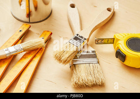 background with a ruler, tape measure, brushes and paint cans on a wooden board Stock Photo
