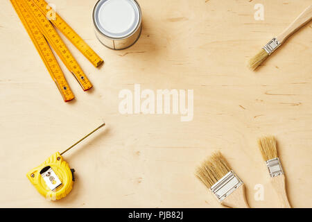 background with a ruler, tape measure, brushes and paint cans on a wooden board Stock Photo