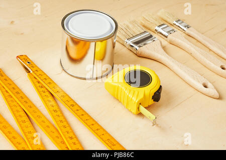 background with a ruler, tape measure, brushes and paint cans on a wooden board Stock Photo