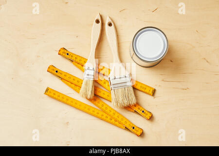 background with a ruler, paint brushes and paint cans on a wooden board Stock Photo