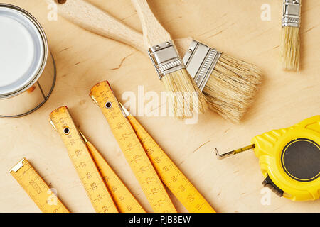 background with a ruler, tape measure, brushes and paint cans on a wooden board Stock Photo