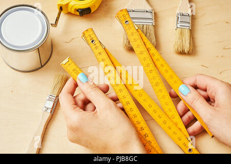 woman holding a ruler in her hands over a wooden table with tools Stock Photo