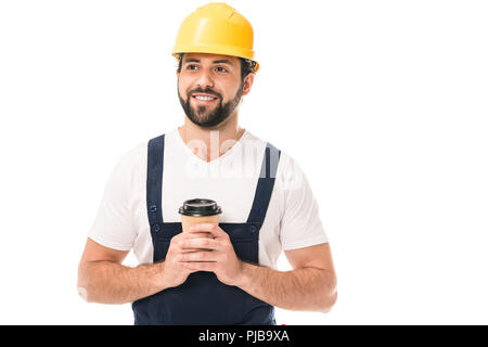handsome smiling workman in hard hat holding coffee to go and looking away isolated on white Stock Photo