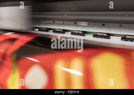 Big professional printer, processing large scale vinyl rolls for color sampling in a massive production enviroment. Stock Photo