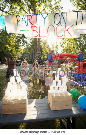 Kids playing water game at summer neighborhood block party in sunny park
