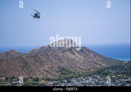HONOLULU, Hawaii (July 2, 2018) An MH-60S Sea Hawk helicopter, assigned to Helicopter Sea Combat Squadron (HSC) 8, flies above Diamond Head State Monument during Rim of the Pacific (RIMPAC) exercise, July 2. Twenty-five nations, more than 45 ships and submarines, about 200 aircraft and 25,000 personnel are participating in RIMPAC from June 27 to Aug. 2 in and around the Hawaiian Islands and Southern California. The world’s largest international maritime exercise, RIMPAC provides a unique training opportunity while fostering and sustaining cooperative relationships among participants critical t Stock Photo