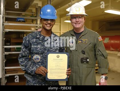 NORFOLK, Va. (July 9, 2018) - Logistics Specialist 3rd Class Javion K. Moore, from Sandusky, Ohio, assigned to USS Gerald R. Ford’s (CVN 78) supply department, receives his certificate of appointment to the rank of petty officer third class from Capt. Richard McCormack, Ford’s commanding officer. Moore was promoted following his selection for the Meritorious Advancement Program. Stock Photo