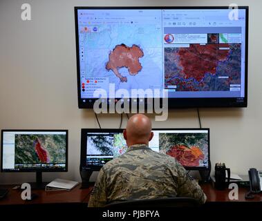 Senior Airman Austin Kingfisher, 234th Intelligence Squadron aerial imagery analyst, provides analysis for the Klamathon Fire July 11, 2018, at Beale Air Force Base, California. The imagery analysts coordinate with crews on the ground, which allow them to fight the fires more effectively. They notify the crews on the ground if the fire has gotten past barriers created by bulldozers or if new fires have been started by embers. During emergencies, they often conduct 24-hour operations until the situation is under control. Stock Photo