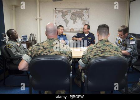 PEARL HARBOR, Hawaii (July 10, 2018) Rear Adm. Cedric Pringle, commander, Expeditionary Strike Group (ESG) 3, left, and Australian Navy Commodore Ivan Ingham, commander, Combined Task Force (CTF) 176, right, conduct an office call with Chilean Navy Commodore Pablo Niemann, combined forces maritime component commander for the 2018 Rim of the Pacific (RIMPAC) exercise, middle left, and his staff in the Flag Mess aboard the amphibious assault ship USS Bonhomme Richard (LHD 6) during the Rim of the Pacific (RIMPAC) 2018 exercise. Twenty-five nations, 46 ships, five submarines, about 200 aircraft a Stock Photo