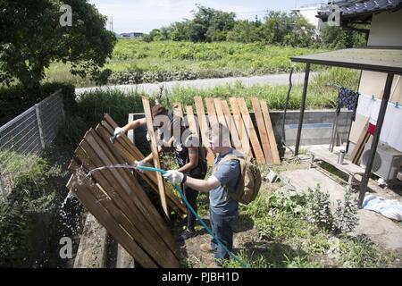 U.S. Marine Corps Lance Cpl. Corey Snyder, right, Lance Cpl. Braelyn Hamilton and Lance Cpl. Joseph Marrero, military policemen with Headquarters and Headquarters Squadron, clean damaged lumber during a volunteer event in Iwakuni City, Japan, July 12, 2018. The volunteer event, organized by the Marine Corps Community Services Single Marine Program, provided service members with the opportunity to help local Japanese residents clean up and recover after the area was flooded by excessive rainfall. Stock Photo