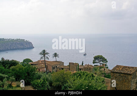 Village and sea landscape with sun and shade and green nuances before thunderstorm in August, Mallorca, Spain.
