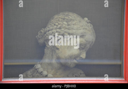 Head of girl sculpture behind a window Stock Photo