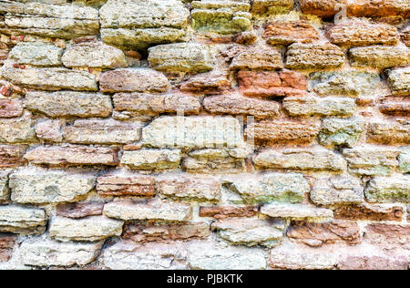 Rough stone wall as creative background texture. Natural stones masonry with uneven seams Stock Photo