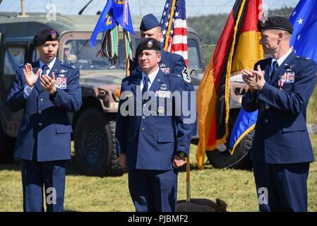 U.S. Air Force Col. J. Brad Reed, left, commander of 4th Air Support Operations Group, and Lt. Col. David Heinitz, right, outgoing commander of 2d Air Support Operations Squadron (2ASOS), give a round of applause to Lt. Col. Michael Hayes as he assumes command of 2ASOS during a change of command ceremony at Rose Barracks, Vilseck, Germany, July 3, 2018. Stock Photo