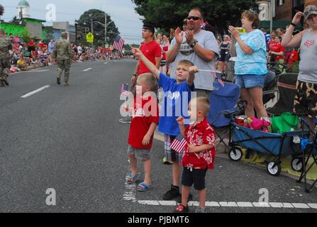 Three boys wave American flags as the 20th CBRNE Command passes by during the July 4th parade in Bel Air, Maryland. Stock Photo