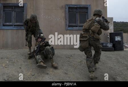 MARINE CORPS BASE CAMP PENDLETON, Calif. (July 10, 2018) – U.S. Marines with 2nd Battalion, 1st Marine Regiment, react to a simulated casualty while patrolling an Infantry Immersion Trainer (IIT) during Rim of the Pacific (RIMPAC) on Marine Corps Base Camp Pendleton, California, July 10, 2018. The IIT provided the Marines with “hands on” practical application of tactical skills and decision making in an immersive, scenario-based training environment. RIMPAC demonstrates the value of amphibious forces and provides high-value training for task-organized, highly capable Marine Air-Ground Task For Stock Photo