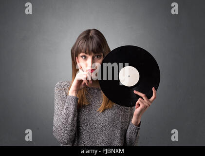 Young lady holding vinyl record on a grey background Stock Photo