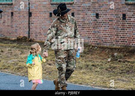 Lt. Col. Timothy Wright, the incoming commander for Battle Group Poland, walks with his daughter Amelia Wright, before a change of command ceremony for the Battle Group Poland at Bemowo Piskie Training Area, Poland on July 14, 2018. Battle Group Poland is a unique, multinational coalition of U.S., U.K., Croatian and Romanian Soldiers who serve with the Polish 15th Mechanized Brigade as a deterrence force in support of NATO’s Enhanced Forward Presence. Stock Photo