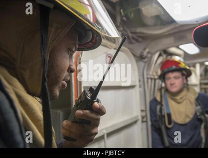 SEA (July 12, 2018) Gunner's Mate 3rd Class Ryan Alexander, from Akroa, Ohio, speaks with damage control central during damage control team training aboard the Harpers Ferry-class dock landing ship USS Oak Hill (LSD 51) July 12, 2018. Oak Hill, homeported in Virginia Beach, Virginia, is conducting naval operations in the U.S. 6th Fleet area of operations in support of U.S. national security interests in Europe and Africa. Stock Photo