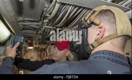 SEA (July 12, 2018) Hull Maintenance Technician 2nd Class Alex Taylor conducts atmospheric testing with a six-gas atmospheric analyzer during damage control team training aboard the Harpers Ferry-class dock landing ship USS Oak Hill (LSD 51) July 12, 2018. Oak Hill, homeported in Virginia Beach, Virginia, is conducting naval operations in the U.S. 6th Fleet area of operations in support of U.S. national security interests in Europe and Africa. Stock Photo