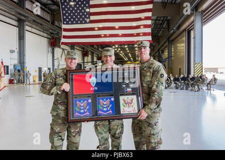 Chief Warrant Officer 5 Douglas W. Phillips, command chief warrant officer, 36th CAB, and Command Sgt. Maj. Robert W. Hartzog, present Col. Ronald W. Burkett II, outgoing commander, 36th CAB, a goodbye present during a change of command, Austin, Texas, July 14, 2018. (Texas Army National Guard Stock Photo