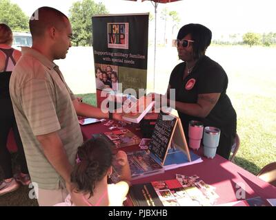 U.S. Marine Corps Community Services School Liasion Officer Latreesa Perryman (left) speaks with Gunnery Sgt. Billy Serpas (right) during the Marine Corps Logistics Base Albany unit's Family Day at Boyett Park. Perryman shares information with Serpas and his twin daughters about family-friendly programs on the installation. Stock Photo