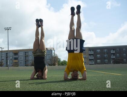 NEWPORT NEWS, Va. (July 12, 2018) Boatswainn’s Mate 2nd Class Cassidy Belcher, from Des Moines, Iowa, left, and Aviation Ordinanceman 3rd Class, from Springdale, Arkansas, do handstands on the field at Huntington Hall at Captain’s Cup. The Nimitz-class aircraft carrier USS George Washington (CVN 73), is undergoing refueling complex overhaul (RCOH) at Newport News Shipyard. RCOH is a nearly four-year project performed only once during a carrier’s 50-year service life that includes refueling of the ship’s two nuclear reactors, as well as significant repair, upgrades and modernization. Stock Photo