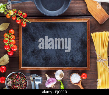 empty black frame and ingredients for cooking pasta on a brown wooden table, copy space Stock Photo