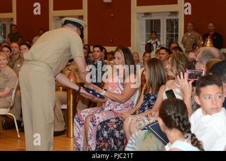 Master Chief James Baker presents a folded flag to his wife during his retirement ceremony at Marston Pavilion aboard Marine Corps Base Camp Lejeune July 13, 2018. Baker served 30 years in the United States Navy. His career included nearly two decades serving as a Special Amphibious Reconnaissance Corpsman. Baker's more recent role was Command Master Chief at Naval Medical Center Camp Lejeune. Stock Photo