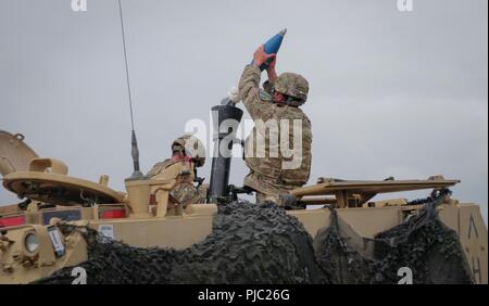 Army Pvt. 1st Class Marcus Escamilla, an assistant gunner assigned to the Headquarters and Headquarters Company, 2nd Battalion, 5th Cavalry Regiment, 1st Armored Brigade Combat Team, 1st Cavalry Division's mortar platoon, loads a 120 millimeter mortar round at a firing range in Smarden, Romania, July 19, 2018. Soldiers conducted a mortar live fire training and evaluation in support of Atlantic Resolve, an enduring training exercise between NATO and U.S. Forces. Stock Photo