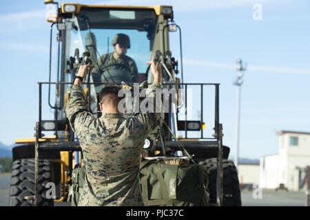 U.S. Marine Corps Pfc. Tanner Cole with the 3d Transportation Support Battalion, directs the transportation of a  container delivery system bundle at the flightline at Joint Base Elmendorf-Richardson, Alaska, July 18, 2018. Marines of the 3d TSB, VMGR-152, and Marine Wing Support Squadron 172 are participating in Exercise Kodiak Mace. During the exercise, through July 25, Marines are conducting joint precision air drop system, cargo, and personnel airdrops. Stock Photo