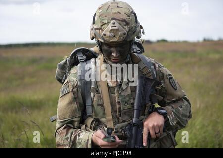 Private 1st Class David Weaver, 1st Battalion, 501st Parachute Infantry Regiment, 4th Infantry Brigade Combat Team (Airborne), 25th Infantry Division, U.S. Army Alaska, navigates across Malemute Drop Zone with a compass at Joint Base Elmendorf-Richardson, Alaska, July 17, 2018. More than 400 Soldiers parachuted as part of a field training exercise, executing tactical movements and setting up defensive positions while performing an airfield assault. Stock Photo