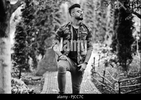 Awesome beautiful tall ararbian beard macho man in glasses and military jacket posed outdoor. Stock Photo