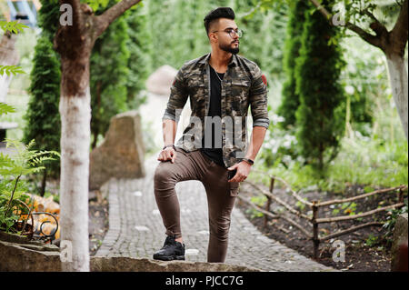 Awesome beautiful tall ararbian beard macho man in glasses and military jacket posed outdoor. Stock Photo