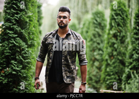 Awesome beautiful tall ararbian beard macho man in glasses and military jacket posed outdoor. Stock Photo