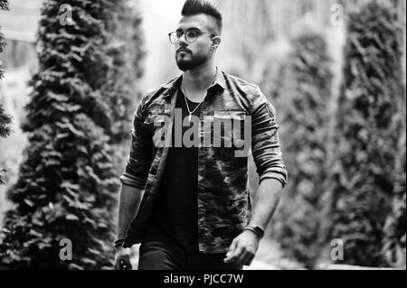 Awesome beautiful tall ararbian beard macho man in glasses and military jacket posed outdoor. Stock Photo