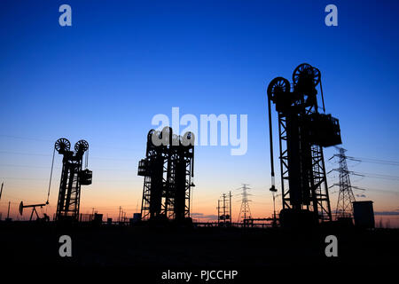 Oil field, the tower type pumping unit in the evening Stock Photo