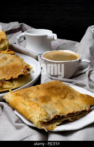 Slices of cherry, apple pie on a white plate and a cup of coffee, jug with cream Stock Photo