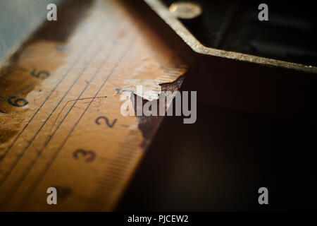 Close up view on 90 degree angle L type ruler with metal handle and numbered label cracking while sitting on plain black table Stock Photo