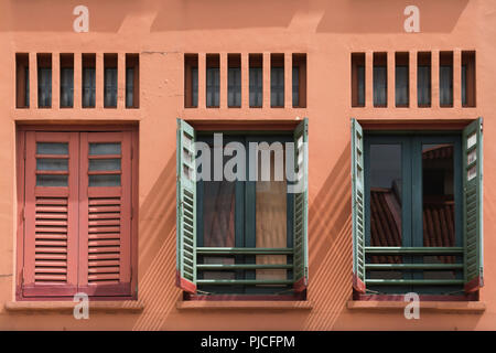 building wall with one closed and two open window shutters in Chinatown of Singapore city Stock Photo