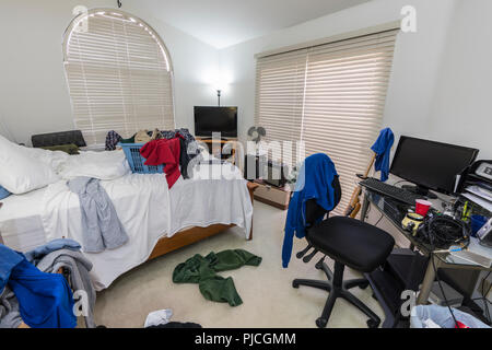 Cluttered, messy teenage boys bedroom with piles of clothes, music and sports equipment. Stock Photo