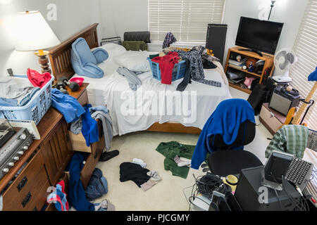 Very messy, cluttered teenage boy's bedroom with piles of clothes, music and sports equipment. Stock Photo