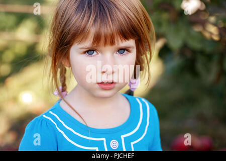 Closeup portrait of cute adorable little red-haired Caucasian girl child with blue eyes looking in camera. Happy childhood  concept Stock Photo