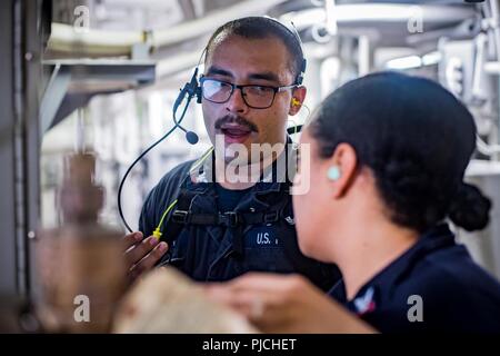 U.S. 5TH FLEET AREA OF OPERATIONS (July 20, 2018) Gas Turbine System Technician (Mechanical) 2nd Class Hector Rosa, left, teaches Damage Controlman 2nd Class Nicole Jackson how to visually inspect a gas turbine generator in a main space aboard the guided-missile destroyer USS Jason Dunham (DDG 109). Jason Dunham is deployed to the U.S. 5th Fleet area of operations in support of naval operations to ensure maritime stability and security in the Central region, connecting the Mediterranean and the Pacific through the western Indian Ocean and three strategic choke points. Stock Photo