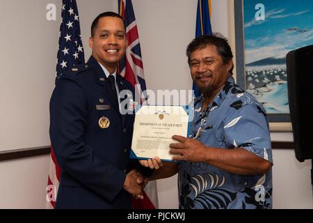 Lt. Col. Wade McGrew, 21st Space Operations Squadron commander, presents the Air Force Civilian Award for Valor to Robin Albios, Detachment 3, 21st SOPS heating, ventilation and air conditioning specialist, at the Kaena Point Satellite Tracking Station, Hawaii, July 23, 2018. Two years ago, Albios provided medical aid to a state of Hawaii volunteer field crew member who suffered from smoke inhalation during a fire at the Kuaokala Game Management Area. Stock Photo